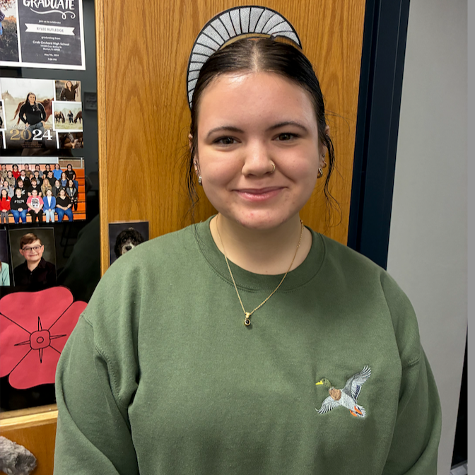 high school female with dark hair pulled back wearing a green sweat shirt with a duck on the front