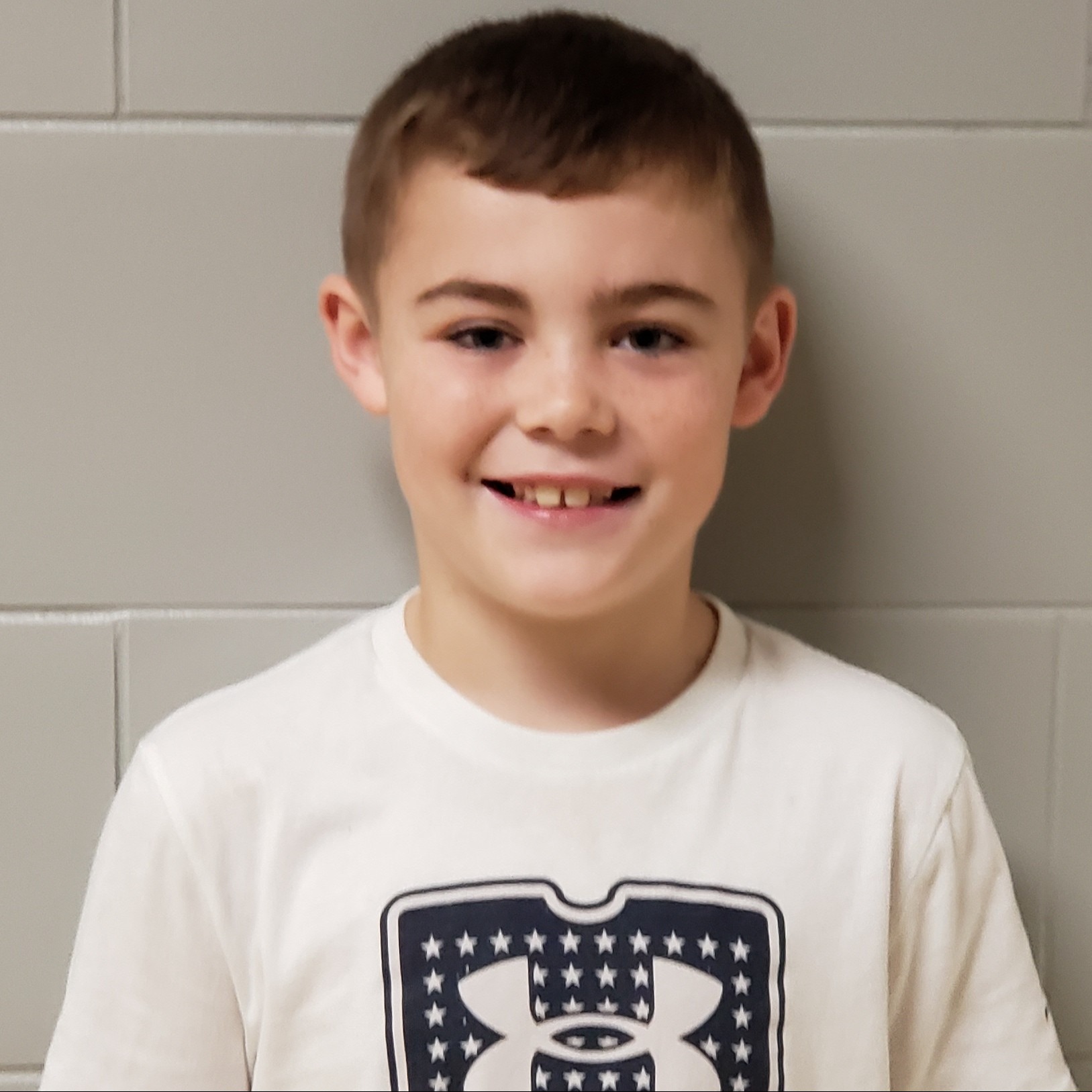 smiling boy with dark hair wearing a white t-shirt