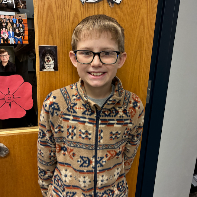smiling junior high boy with blonde hair wearing glasses and a aztec print jacket