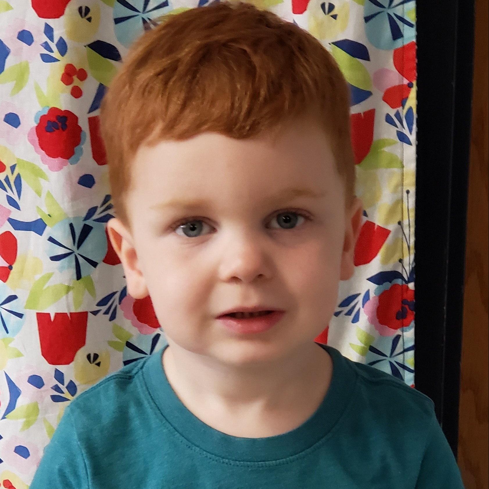 little boy with red hair wearing a teal t-shirt