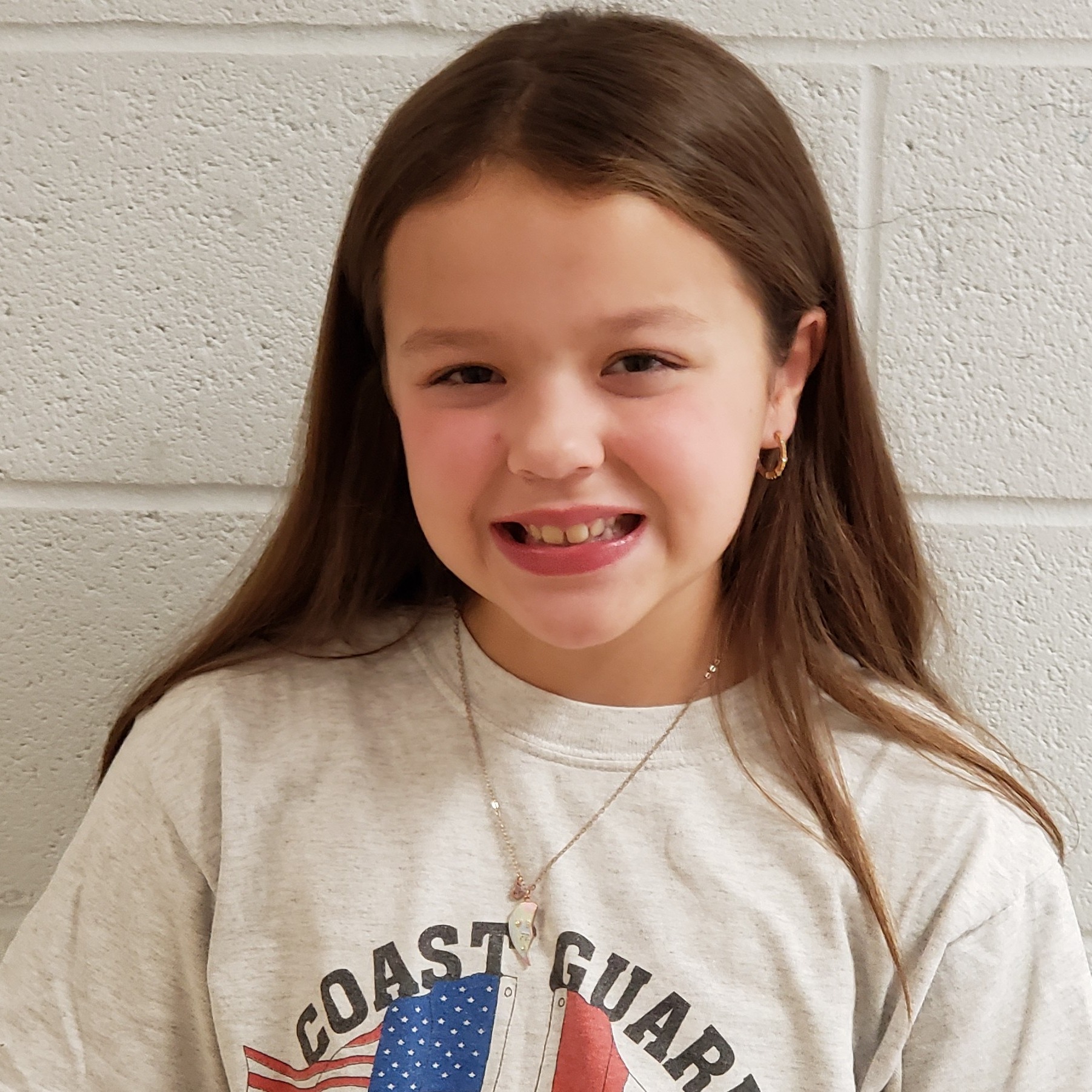 smiling girl with brown hair wearing a gray Coast Guard t-shirt