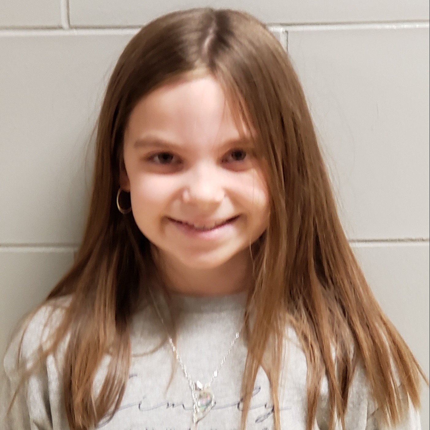 smiling girl with long-brown hair wearing a gray sweatshirt