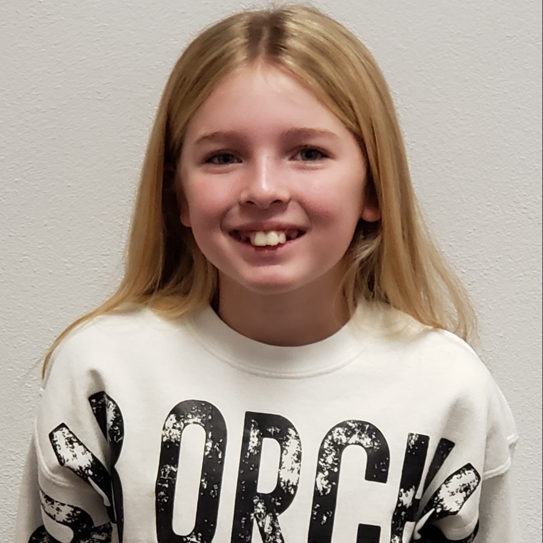 smiling girl with blonde hair wearing a white sweatshirt