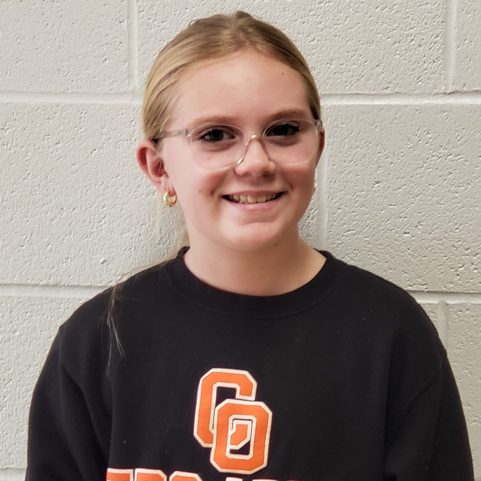 smiling girl with blonde hair pulled back wearing a black CO Trojans sweatshirt