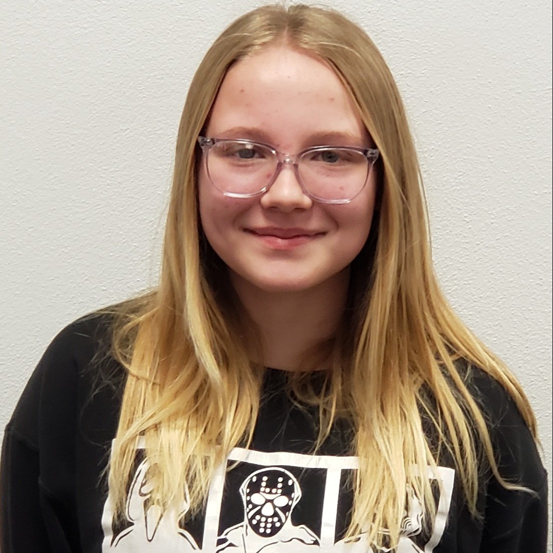 smiling young lady with blonde hair and clear glasses wearing a black sweatshirt