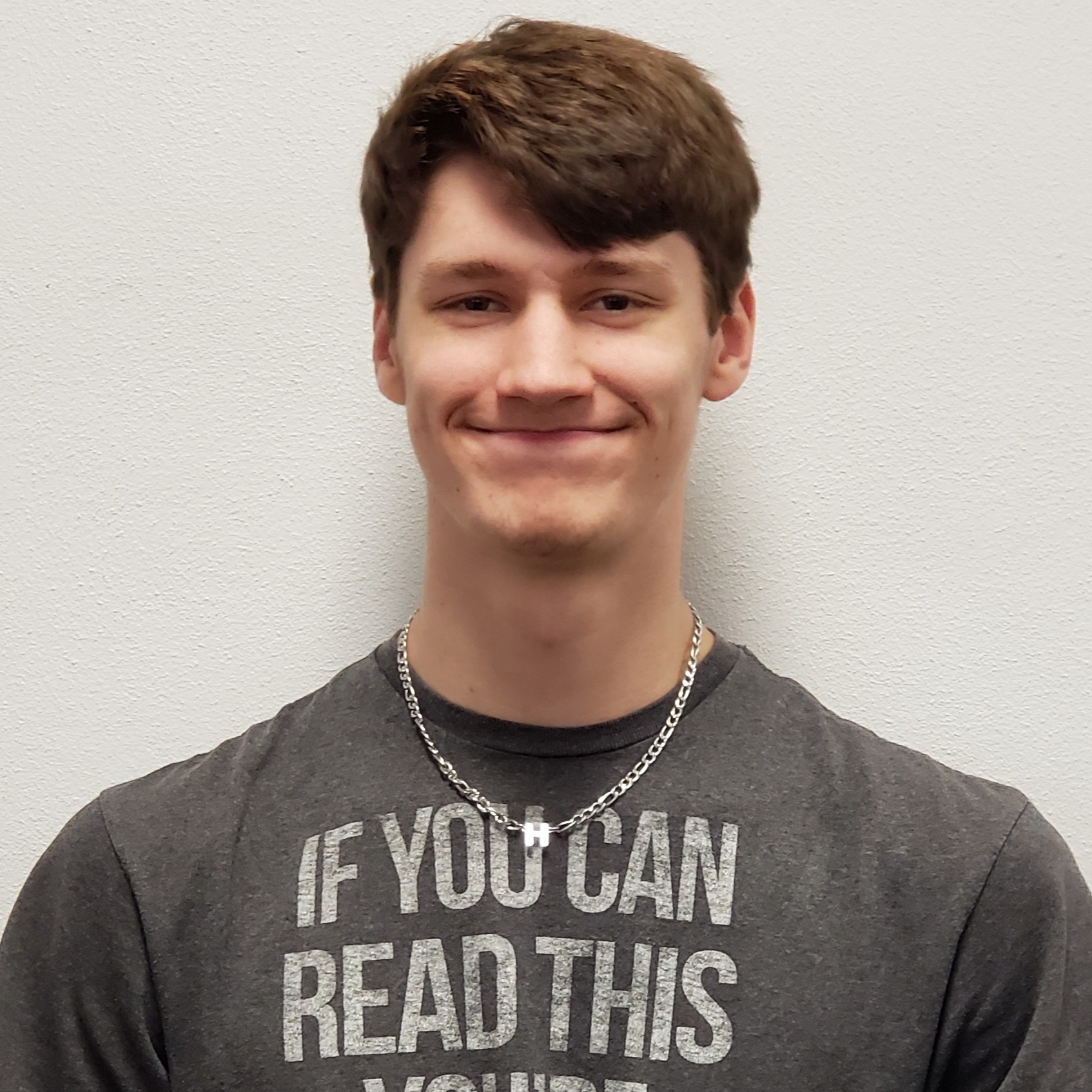 smiling young man with brown hair wearing a dark gray t-shirt