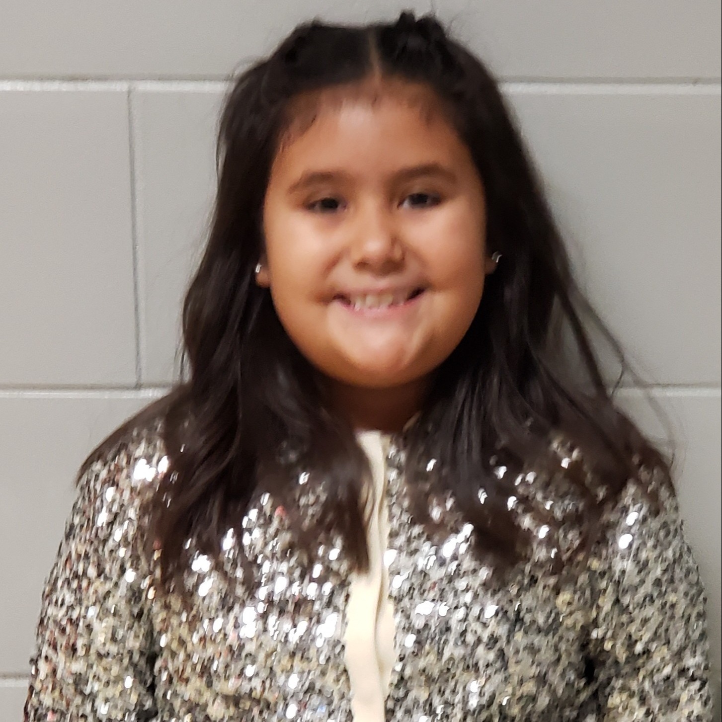 smiling girl with black hair wearing a sparkly jacket