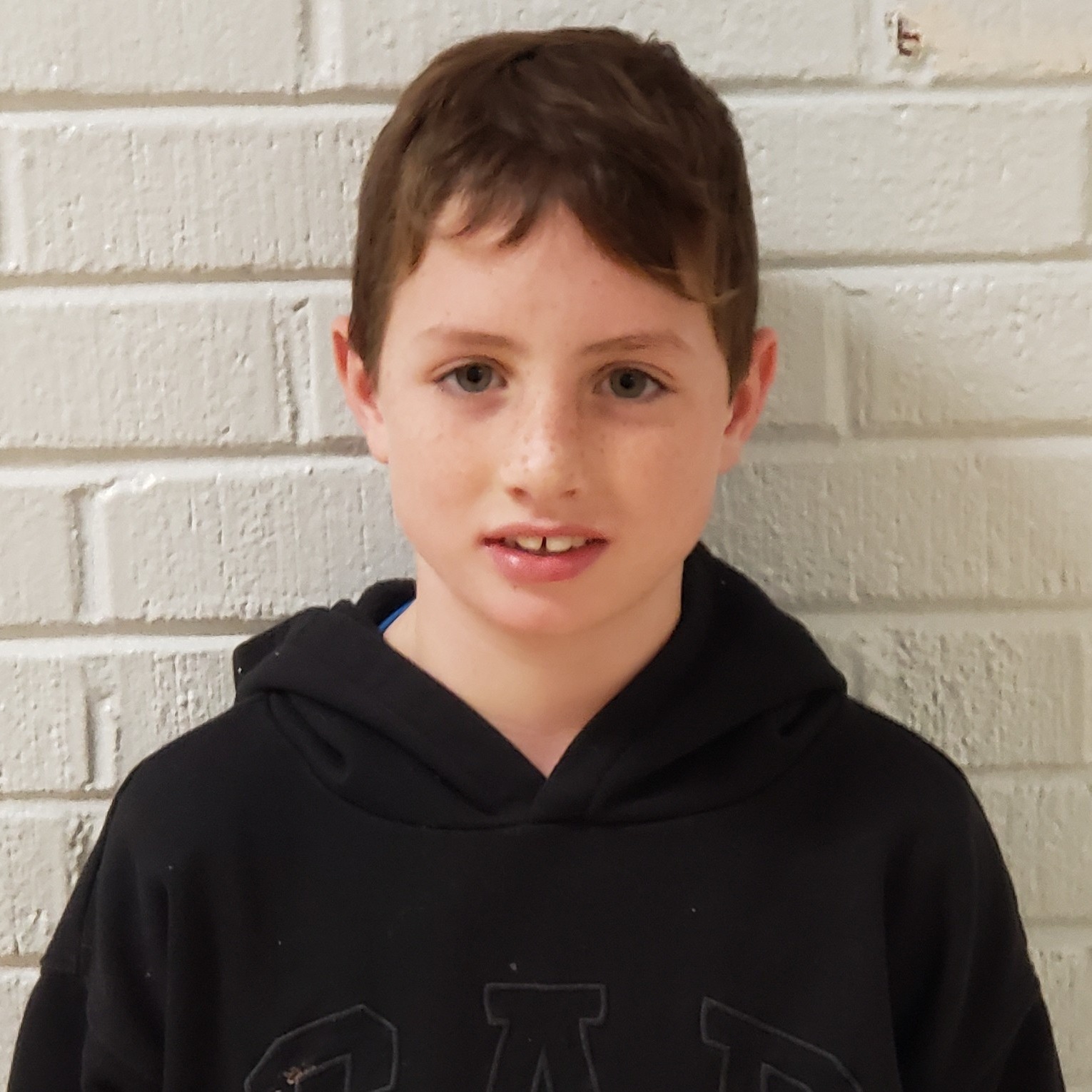 boy with reddish brown hair wearing a black hoodie