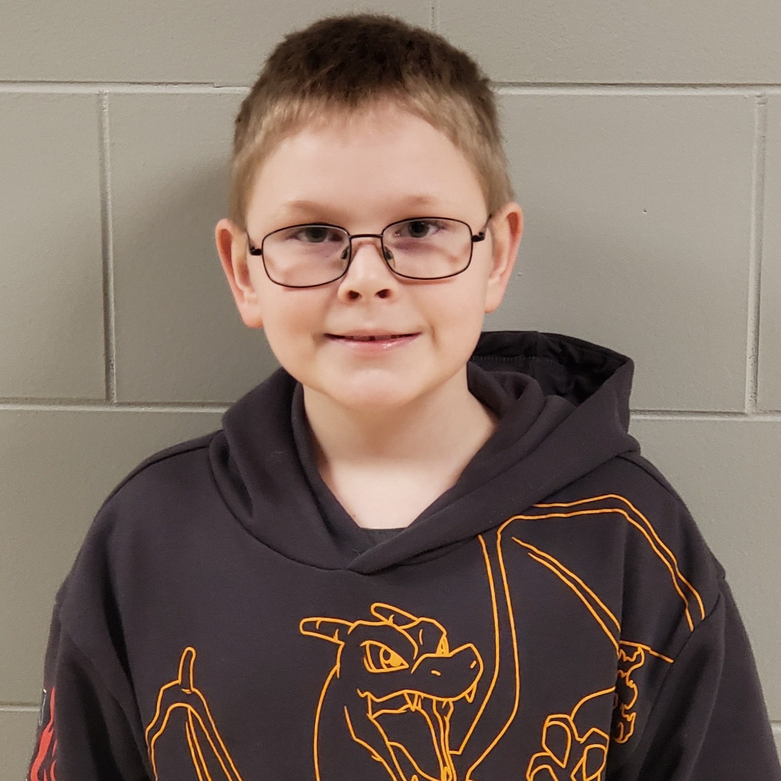 boy with dark blonde hair and glasses wearing a gray hoodie