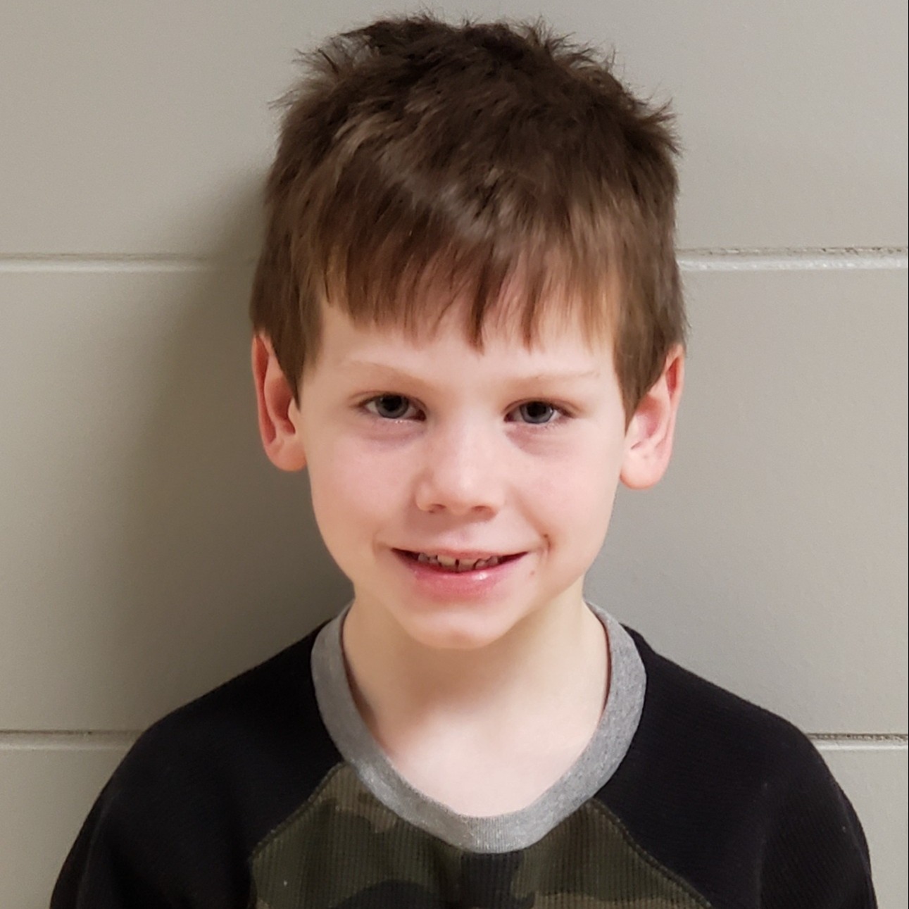 smiling boy with reddish hair wearing a camouflage & black shirt