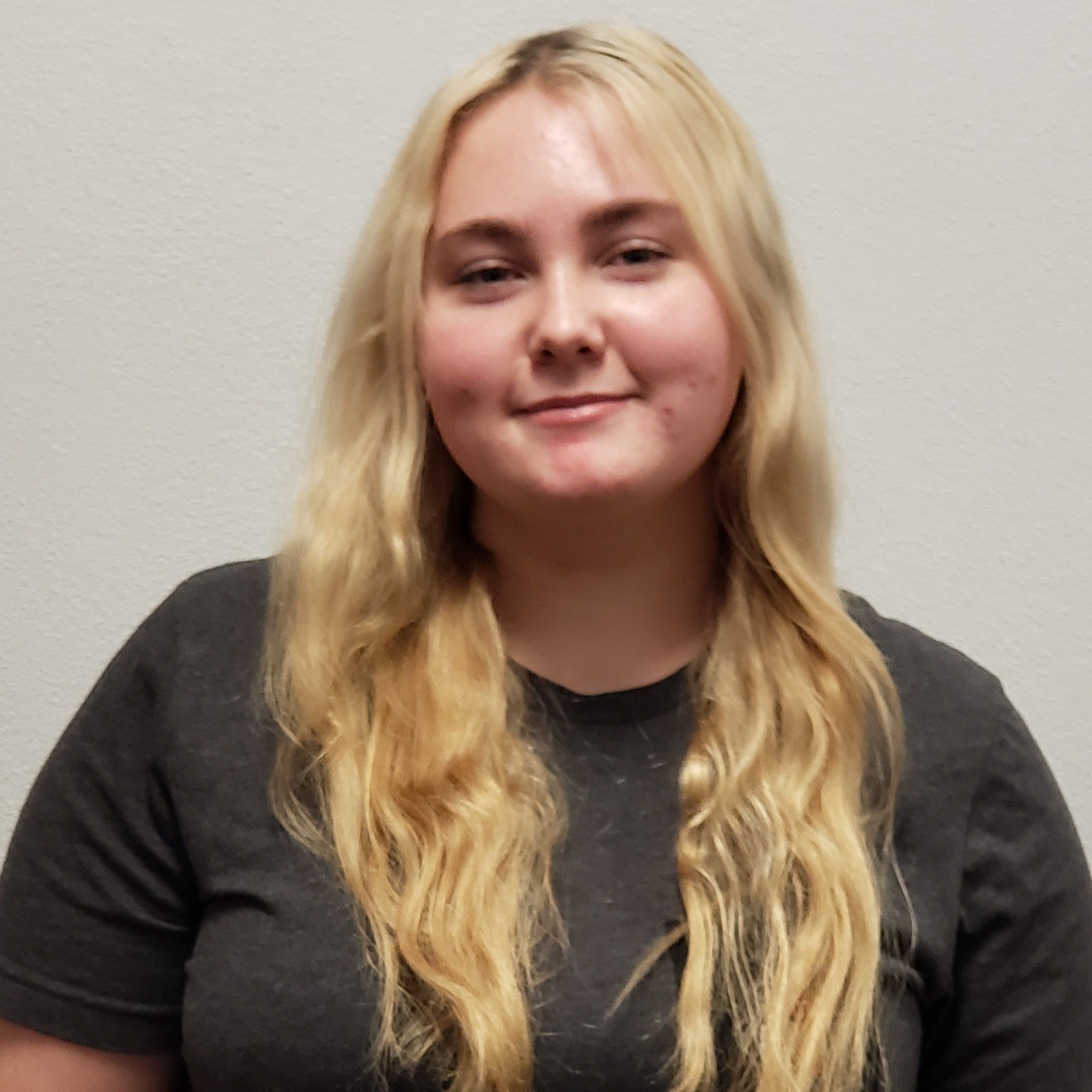 smiling young lady with blonde hair wearing a dark gray t-shirt