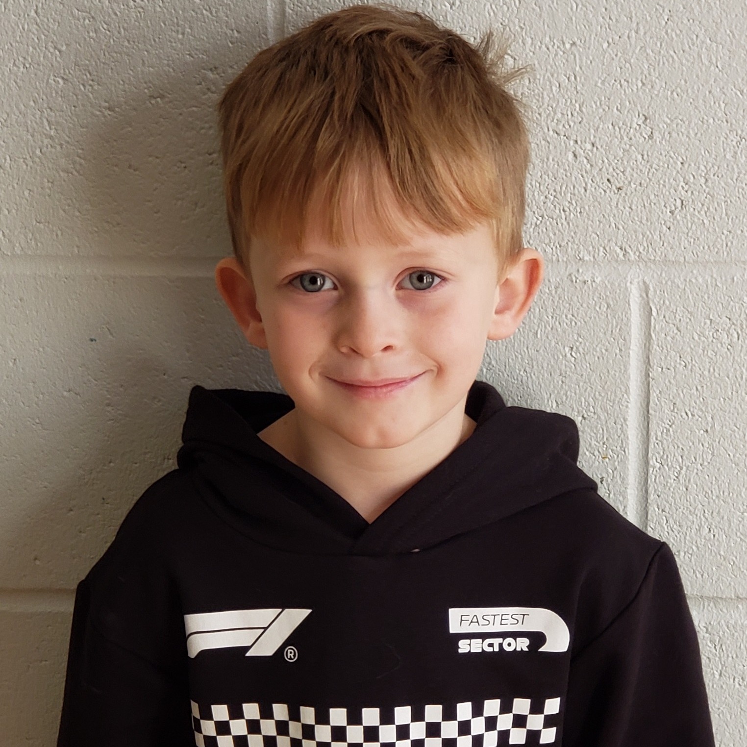 smiling little boy with blonde hair wearing a black hoodie