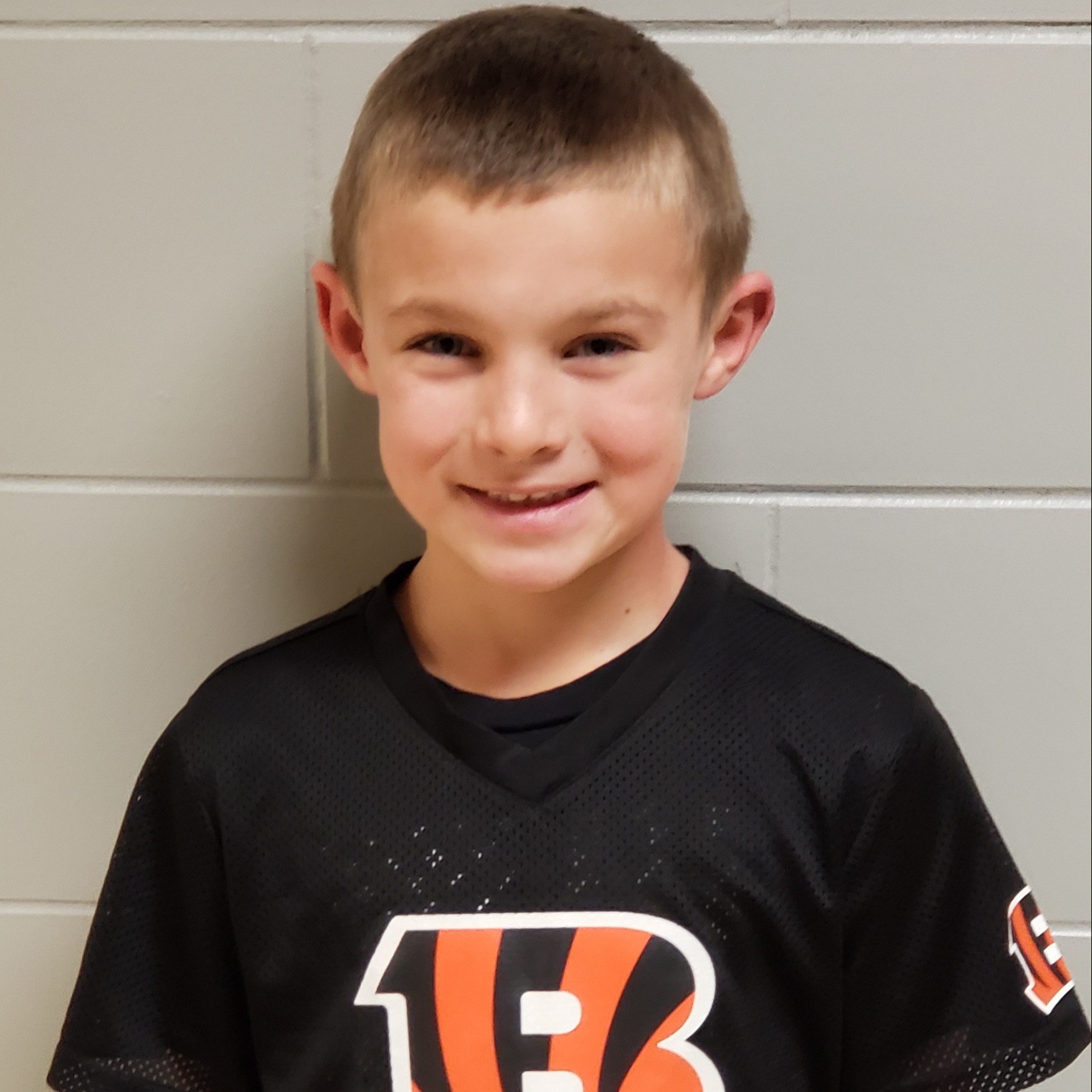 smiling boy with dark blonde hair wearing a Chicago Bears jersey