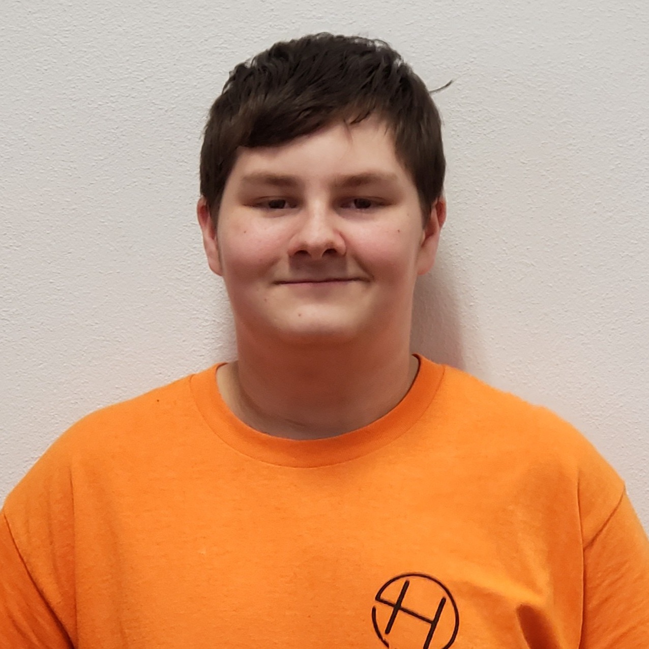 grinning young man with dark hair wearing an orange t-shirt