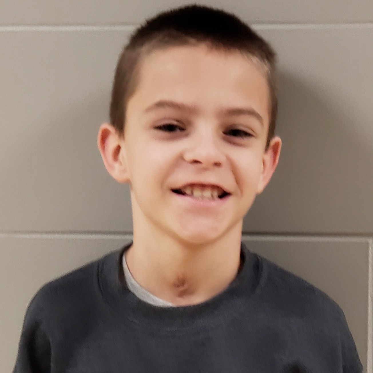 smiling boy with brown hair  wearing a dark gray sweatshirt