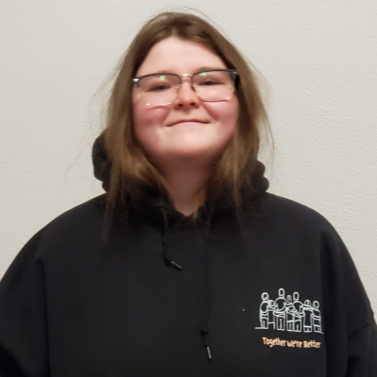 smiling young lady with reddish brown hair and glasses wearing a black hoodie
