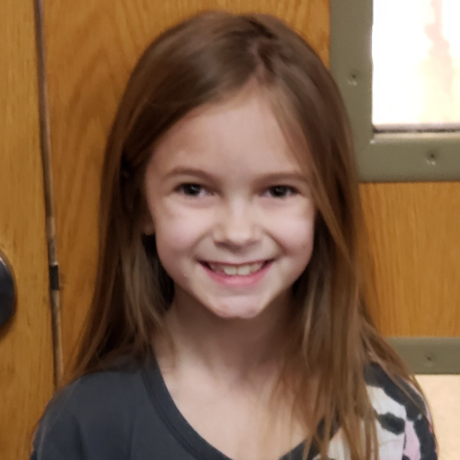 smiling girl with brown hair wearing a dark gray t-shirt