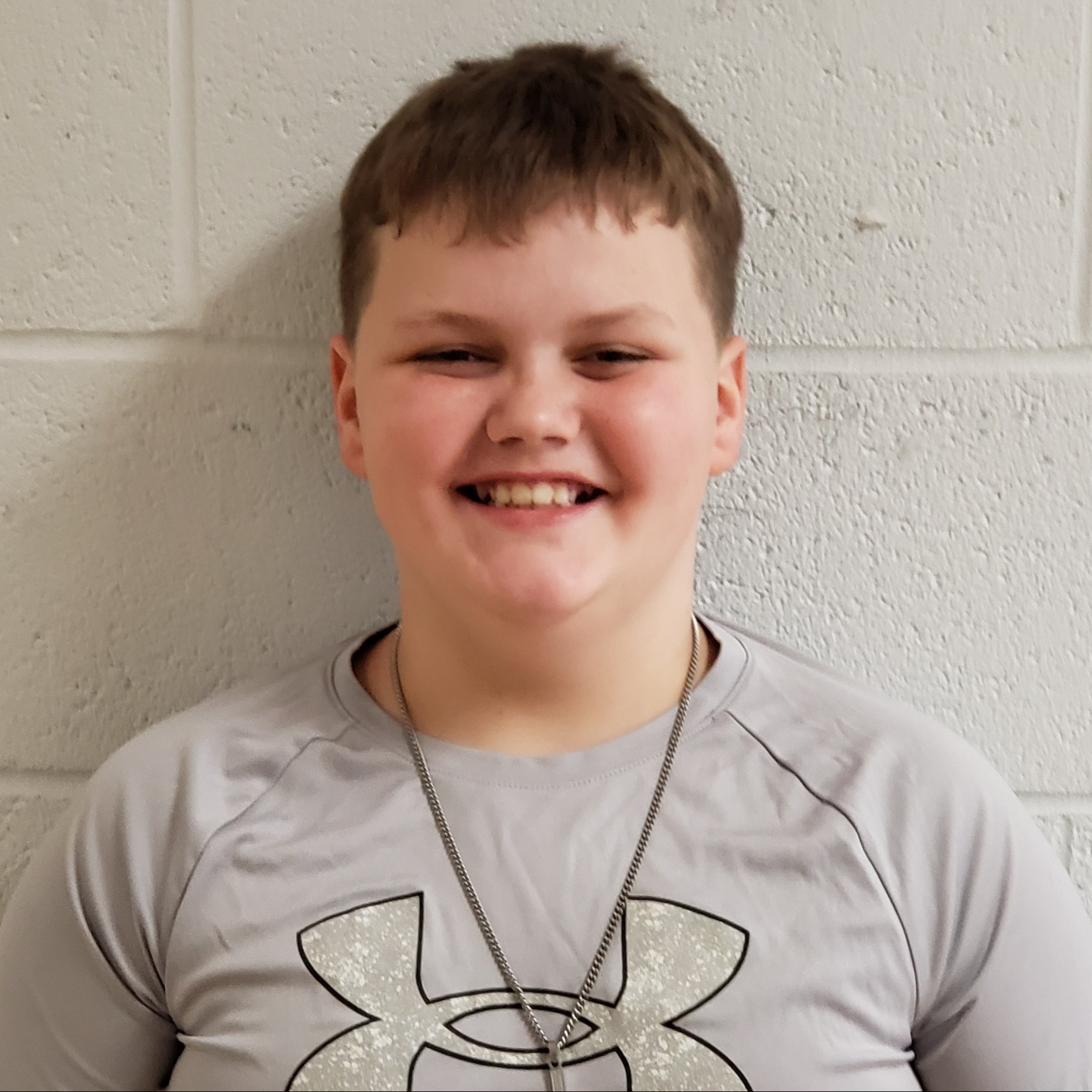 smiling boy with dark hair wearing a gray t-shirt