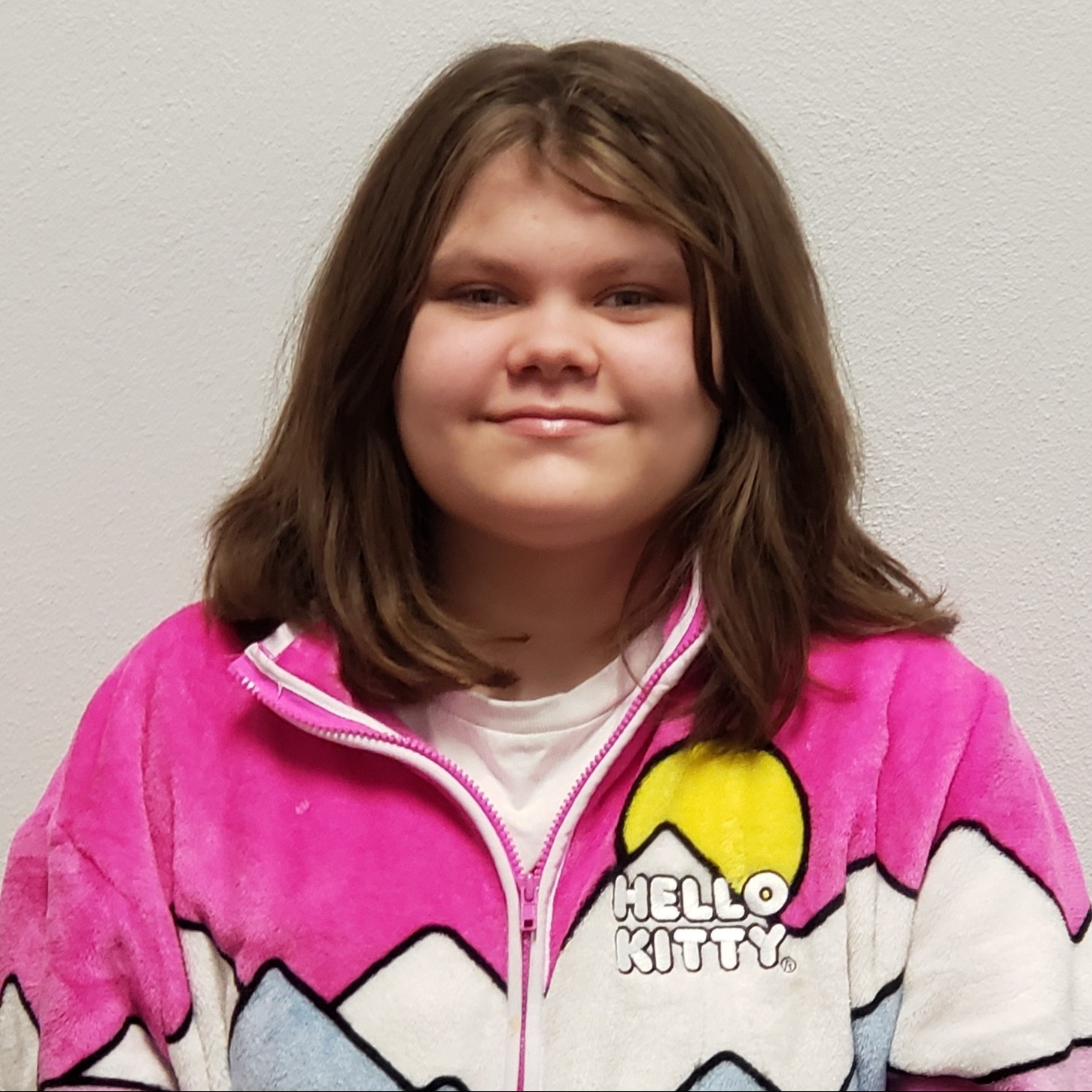 grinning girl with dark hair wearing a white t-shirt under a pinl & white Hello Kitty jacket