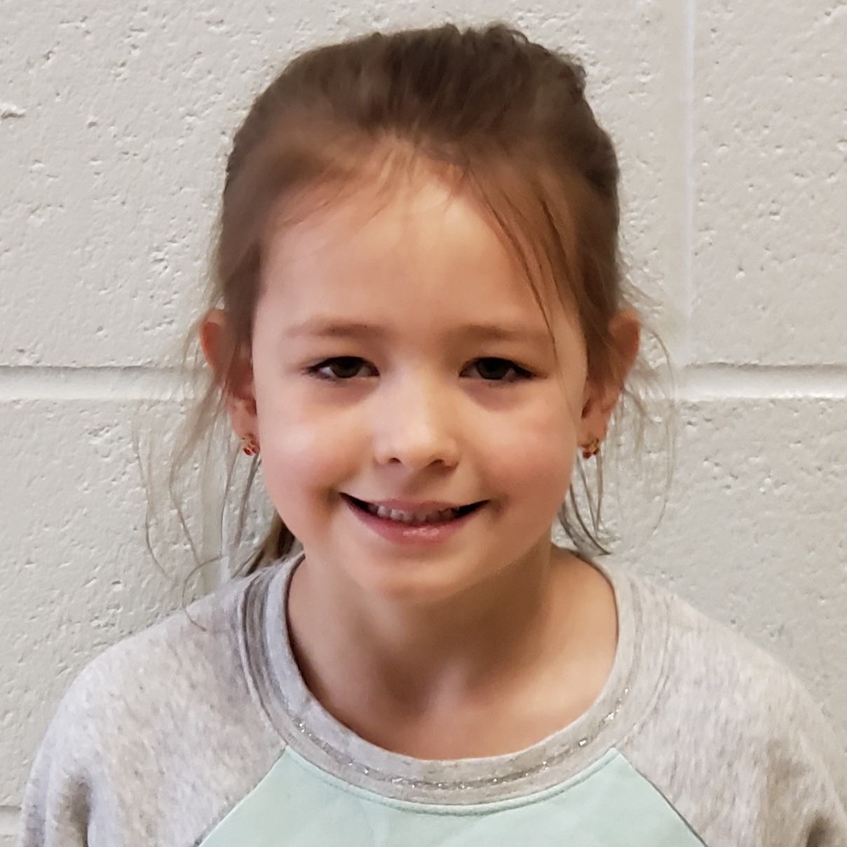 young girl with dark hair pulled back wearing a gray sweatshirt