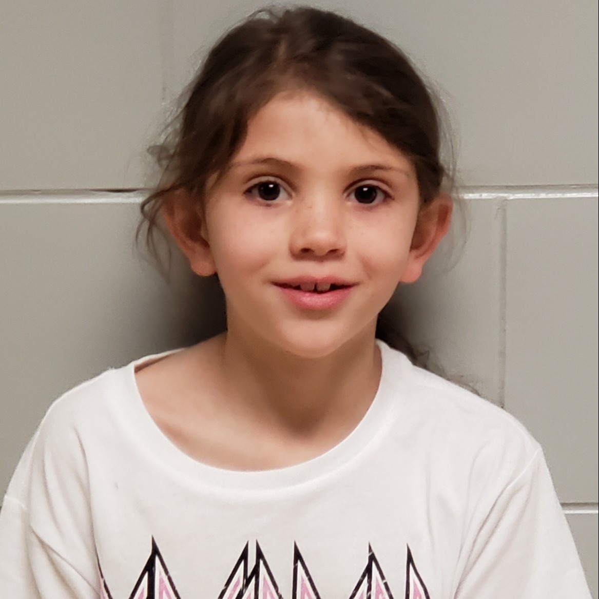 smiling girl with dark hair pulled back wearing a white t-shirt shirt
