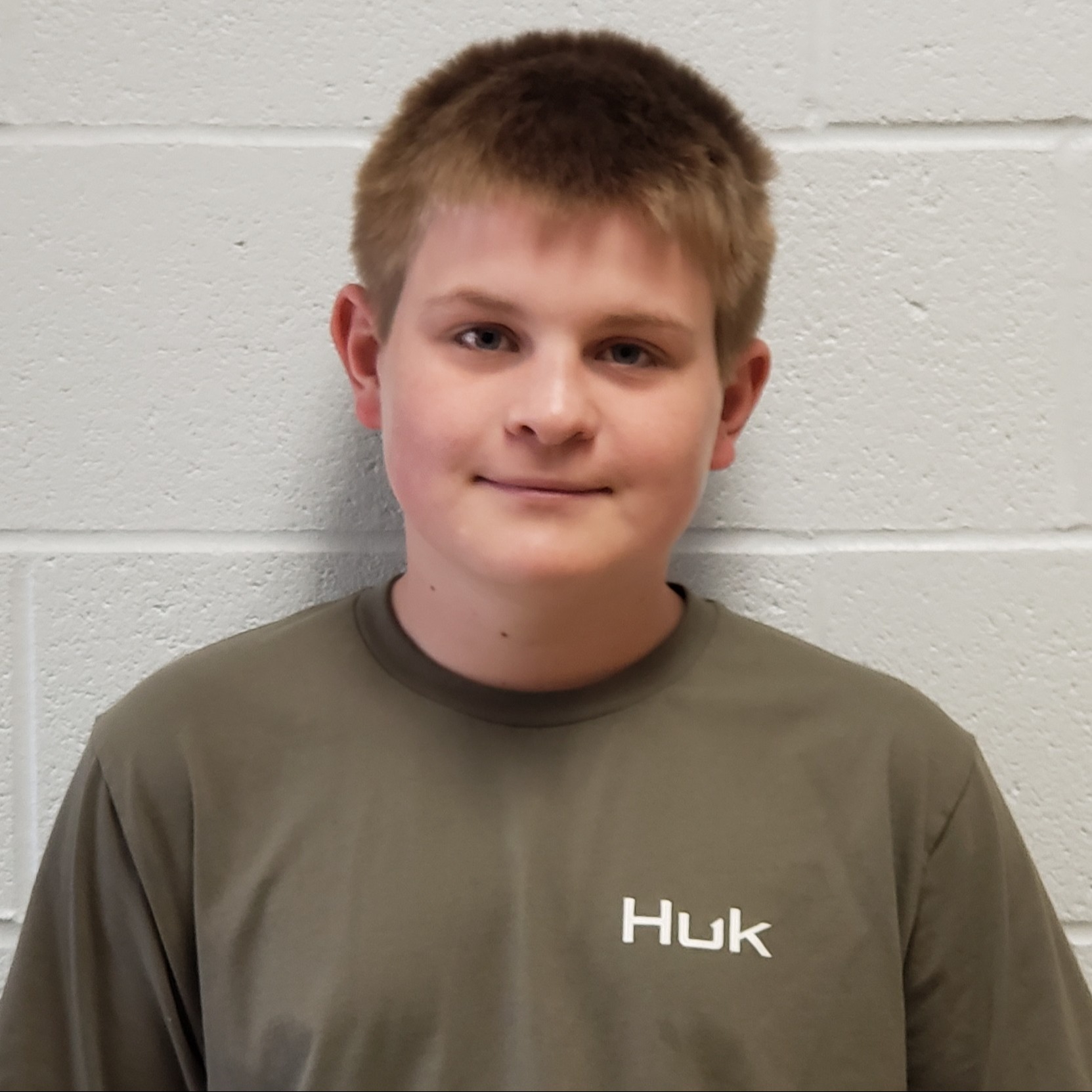 grinning boy with dark blonde hair wearing a gray t-shirt