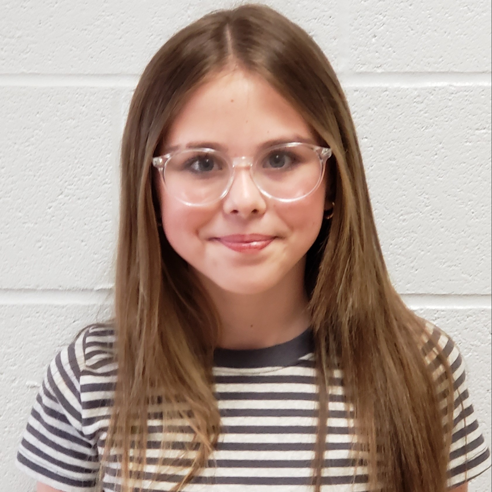smiling girl with dark hair wearing a gray & white striped t-shirt