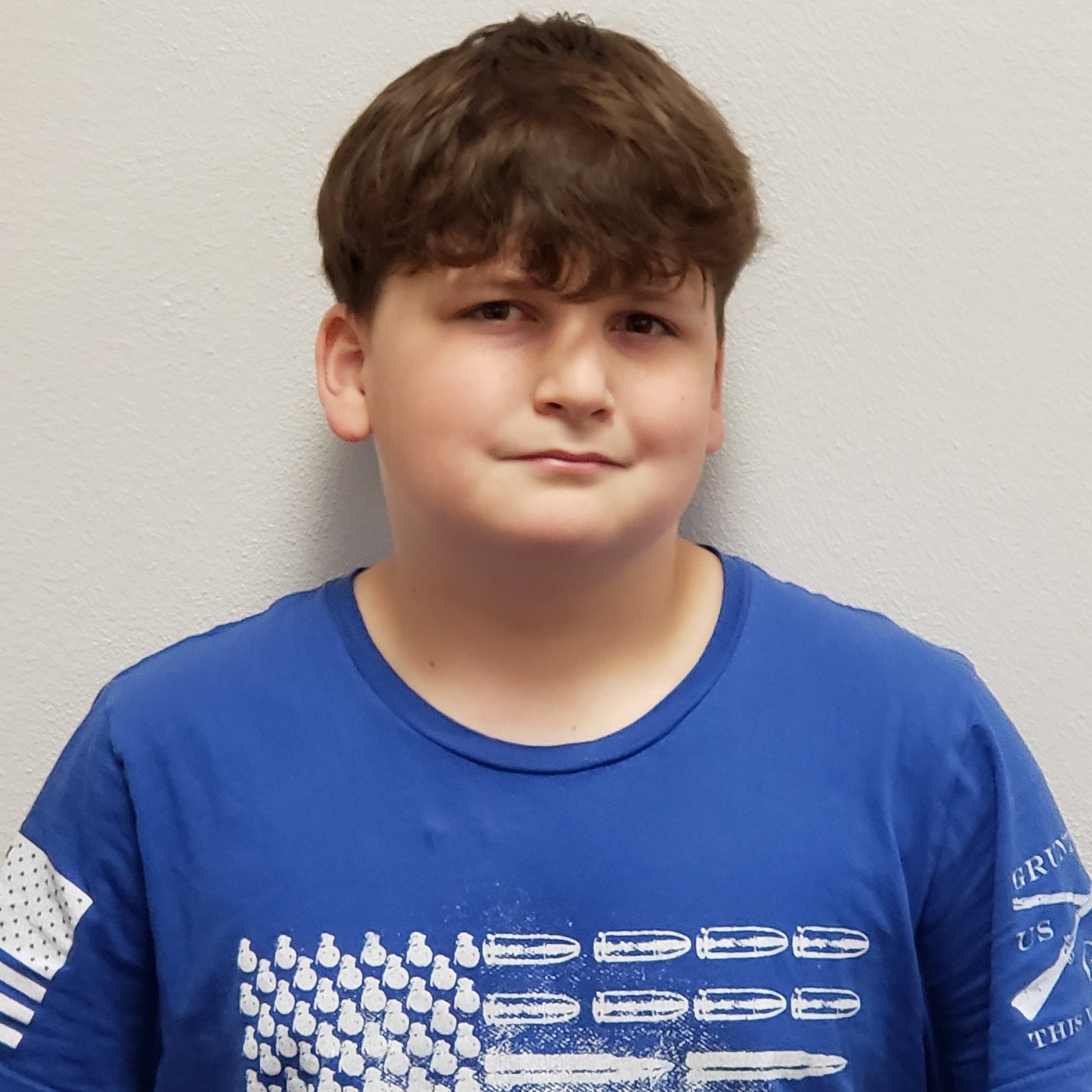 grinning boy with dark hair wearing a blue t-shirt