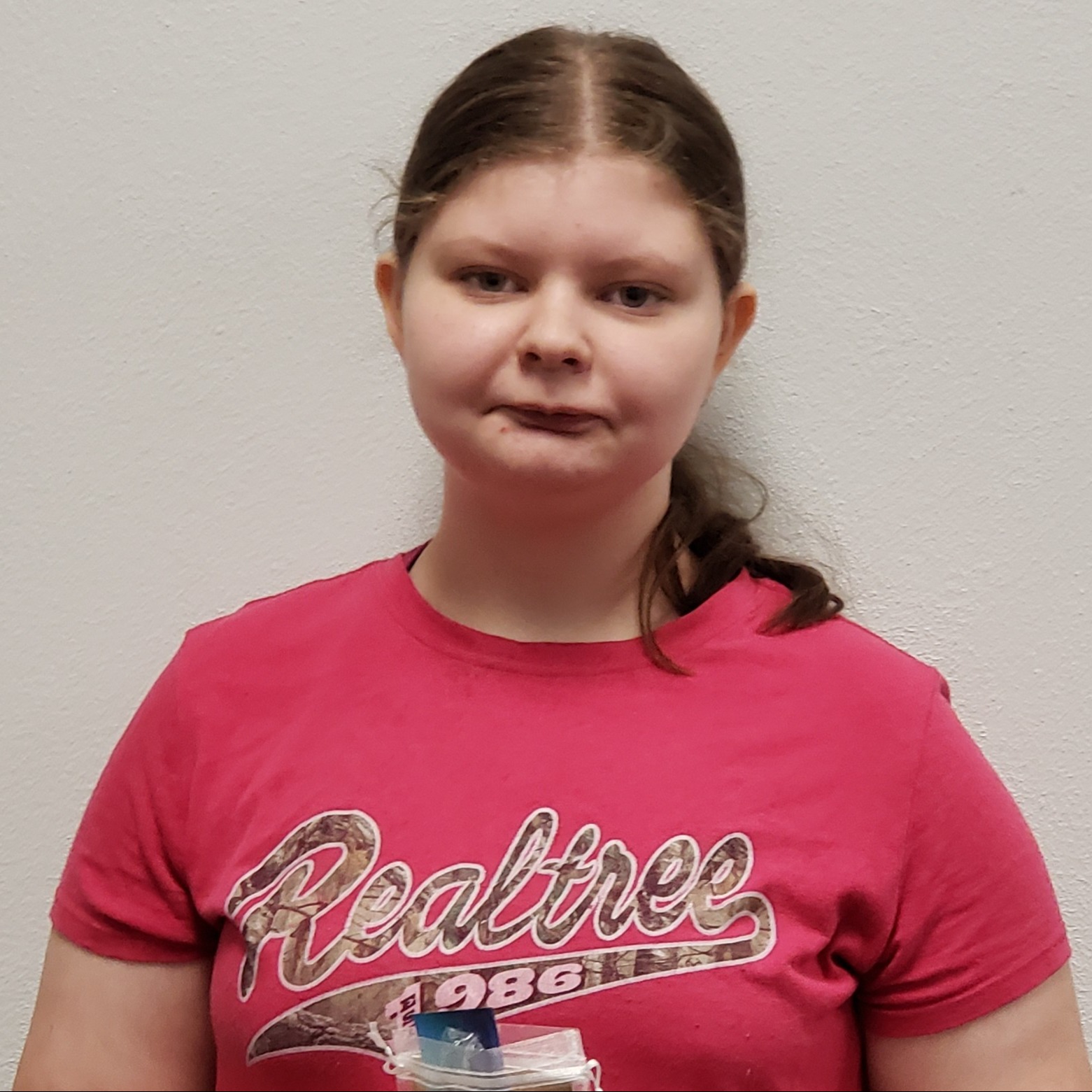 grinning girl with dark hair pulled back wearing a dark pink Realtree t-shirt