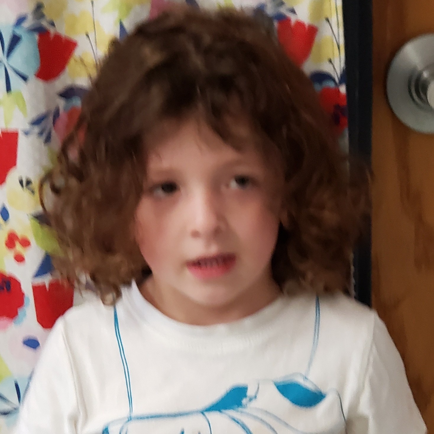young boy with dark curly hair wearing a white t-shirt