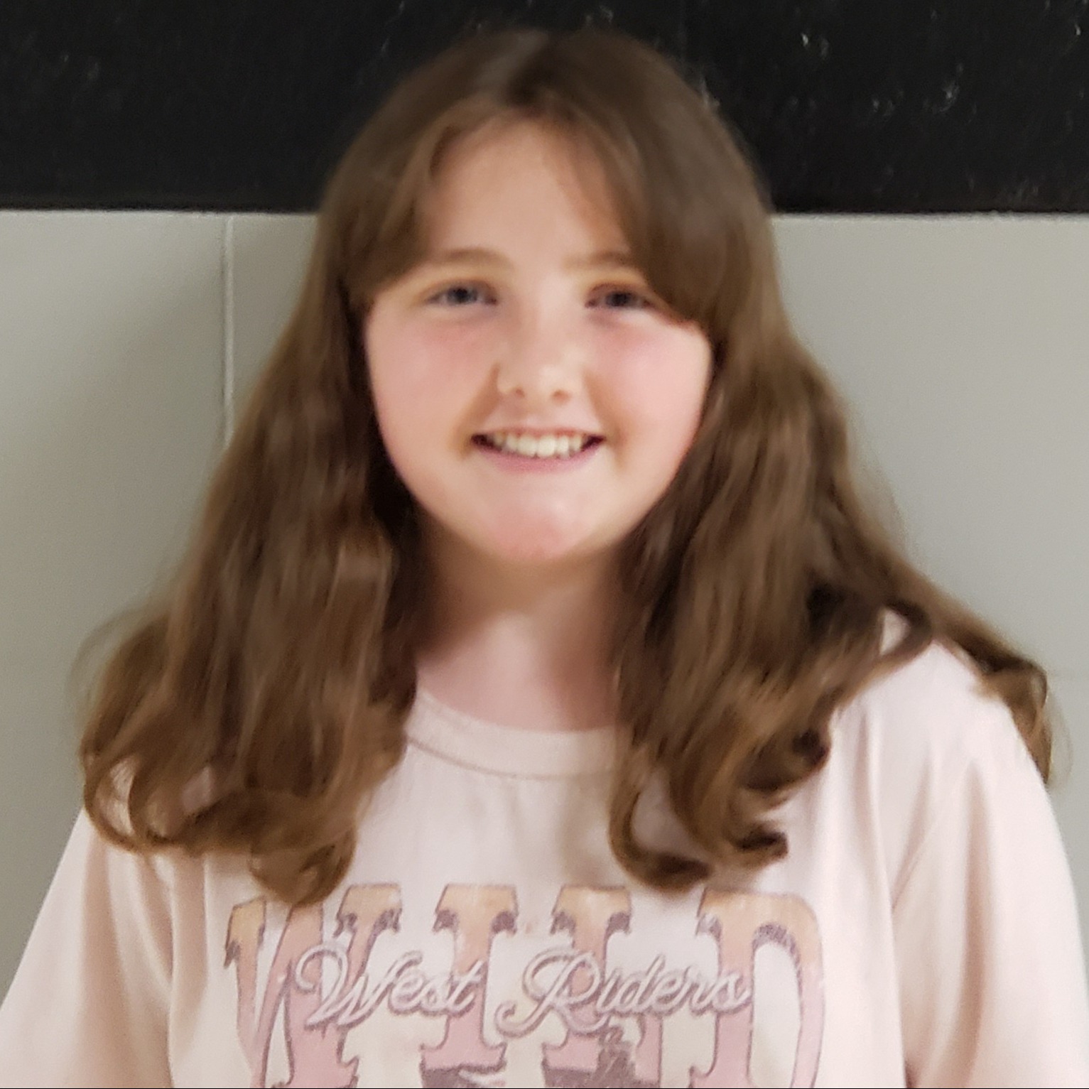 smiling girl with long brown hair  wearing a light pink t-shirt