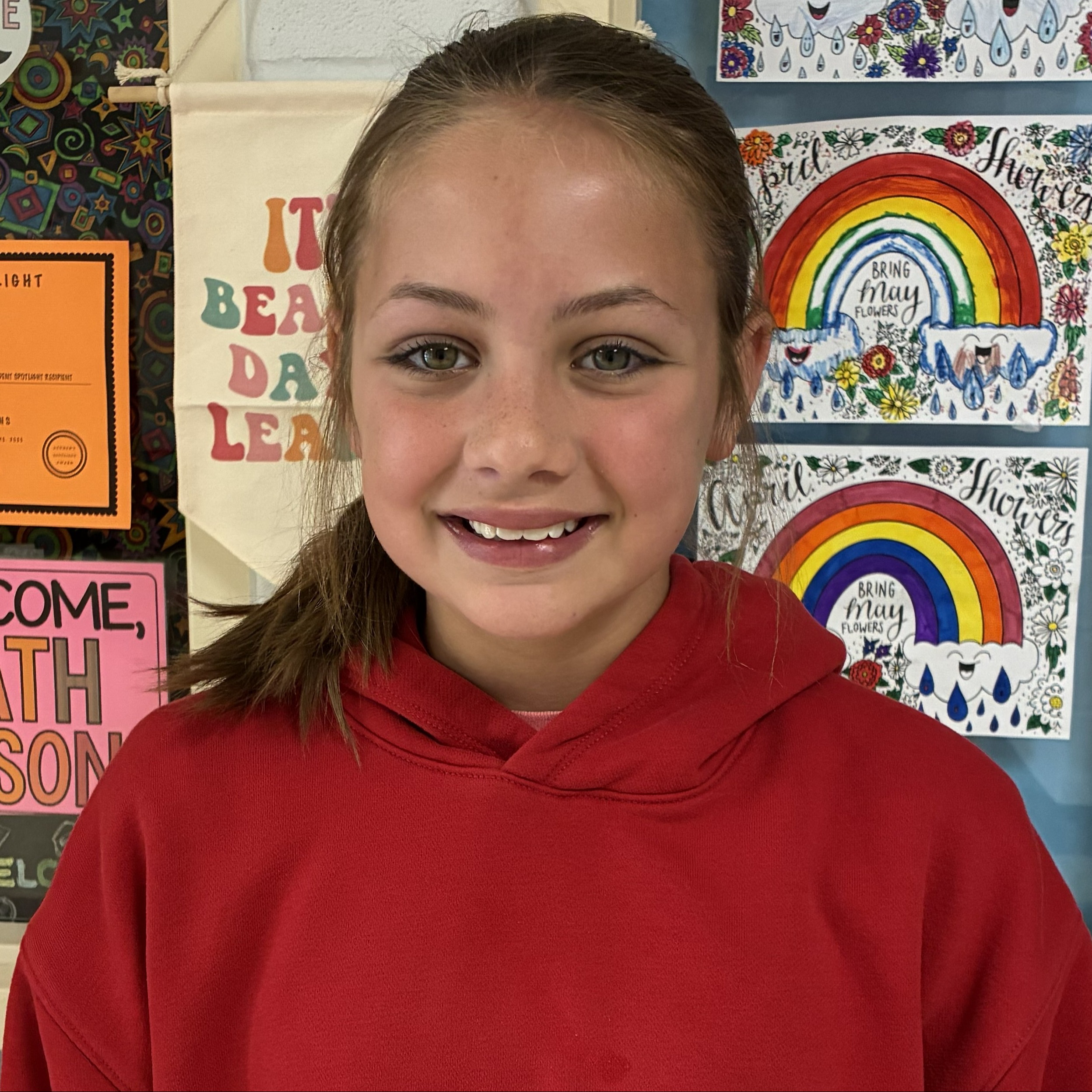 smiling girl with brown hair pulled back wearing a red hoodie
