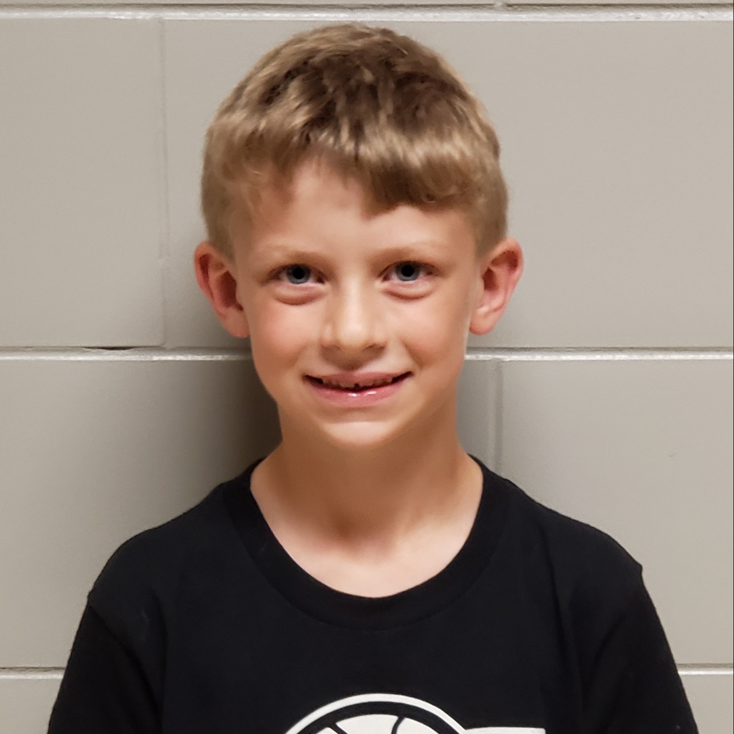 smiling young boy with blonde hair wearing a black t-shirt