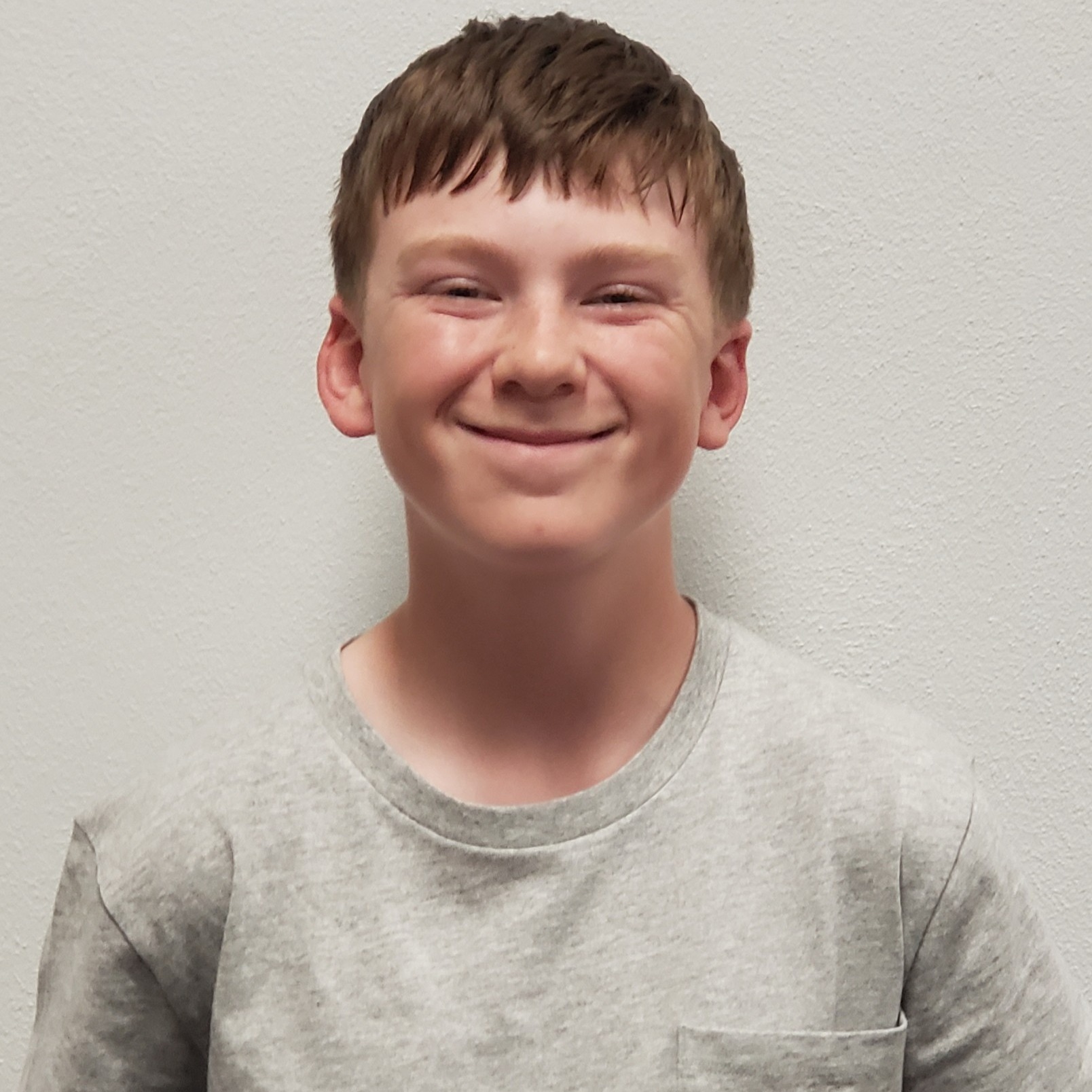 grinning young man with reddish hair wearing a gray t-shirt 