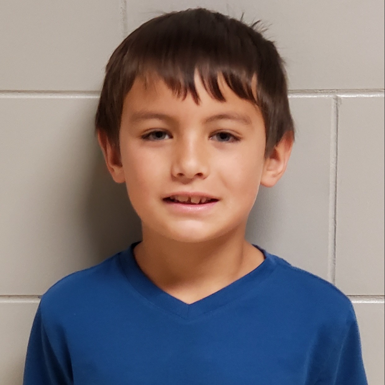 young boy with dark hair wearing a blue t-shirt