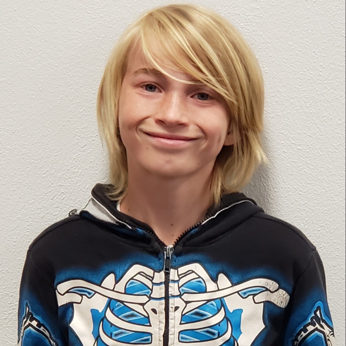smiling boy with blonde hair parted on the side wearing a navy & white skeleton jacket