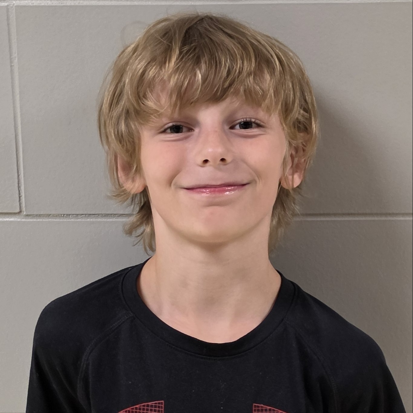 grinning boy with blonde hair wearing a black t-shirt