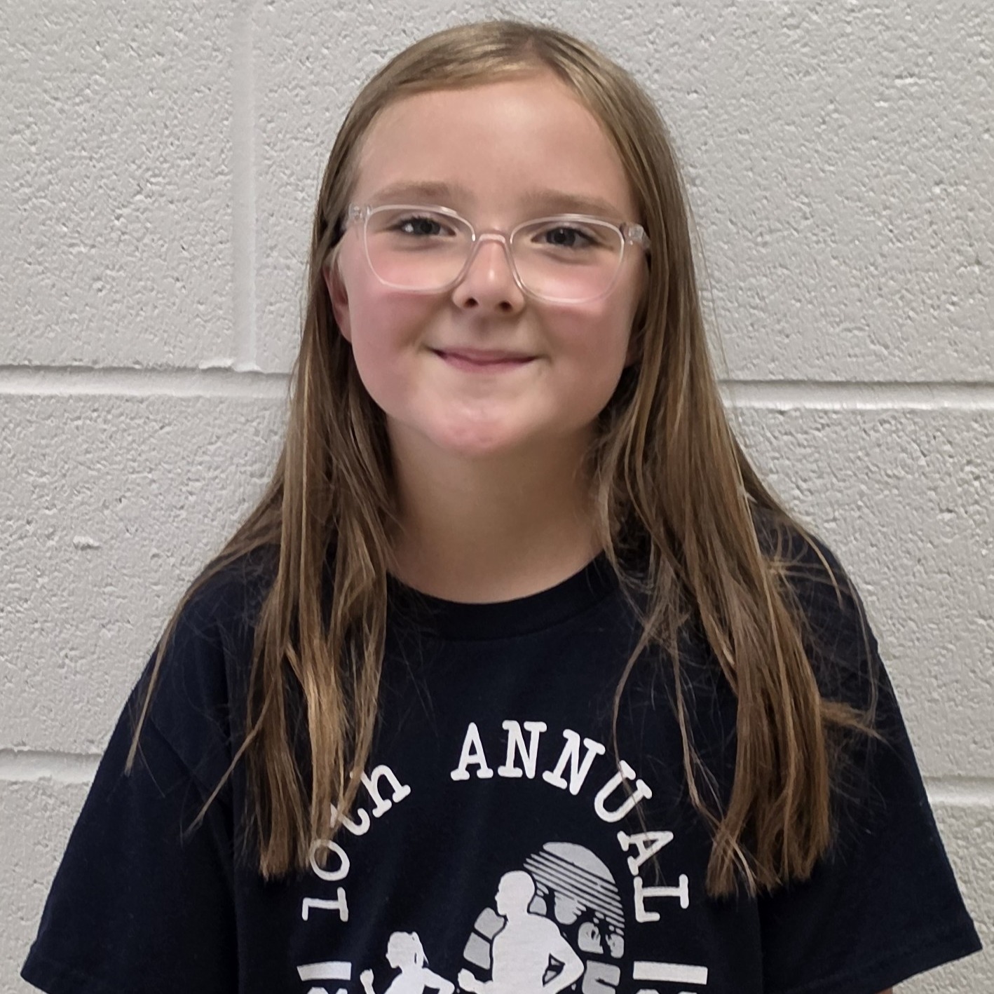 smiling girl with long sandy hair and clear glasses wearing a black t-shirt