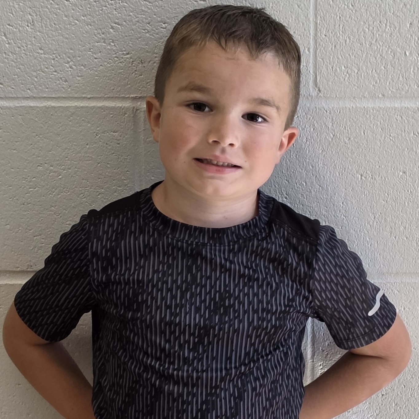 smiling boy with brown hair  wearing a black & gray t-shirt