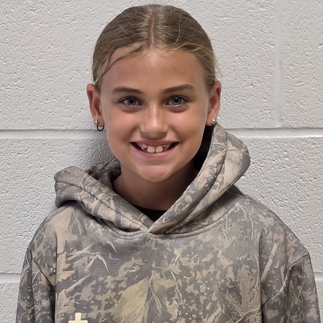 smiling girl with light brown hair pulled back wearing a camouflage hoodie