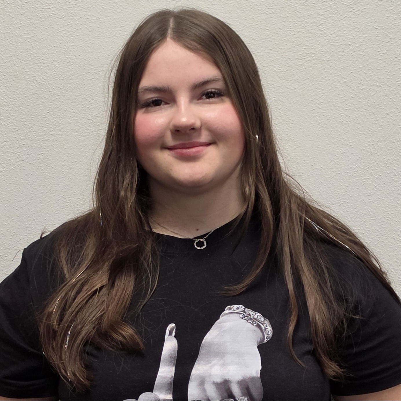smiling young lady with long, brown hair wearing a black t-shirt 