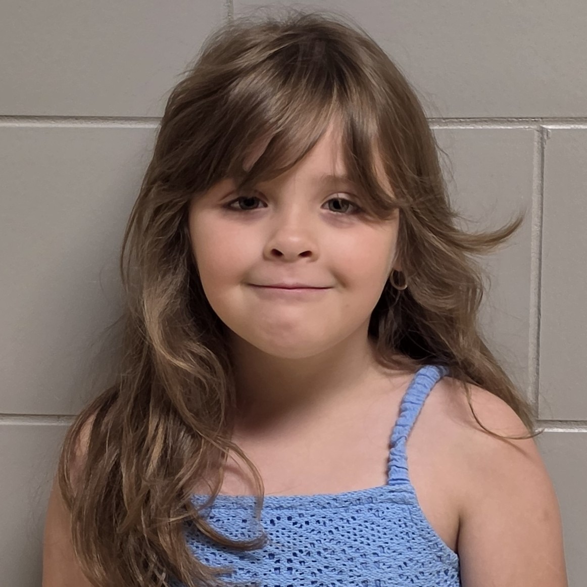 grinning girl with brown hair wearing a blue sundress