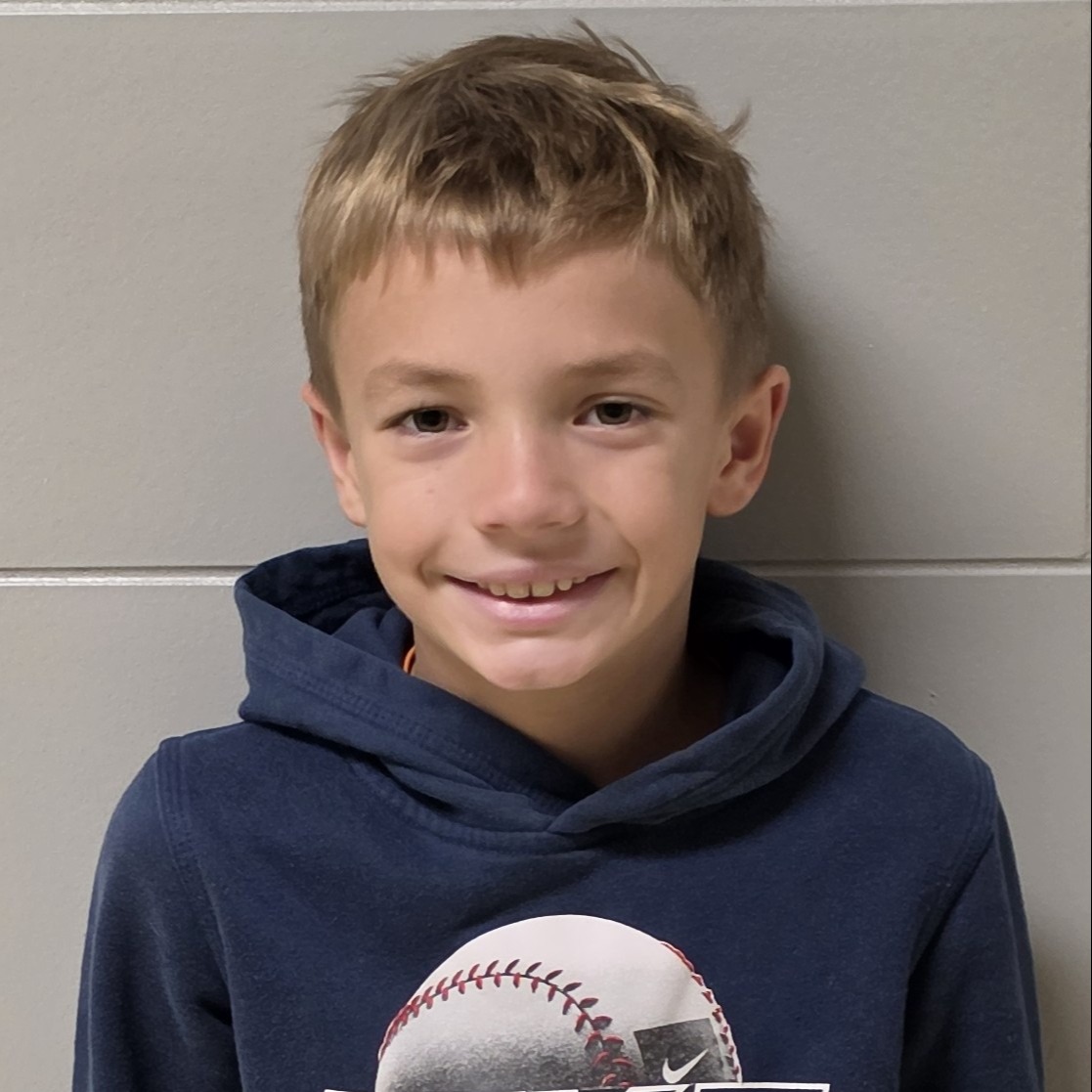 smiling boy with dark blonde hair wearing a dark blue hoodie with a baseball on it
