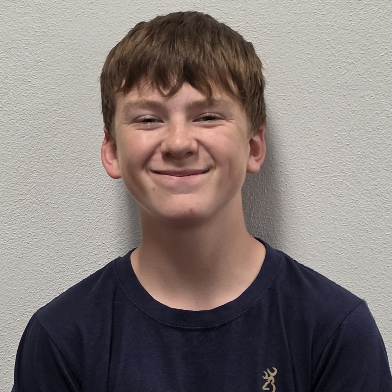 smiling boy with reddish hair wearing a navy blue t-shirt