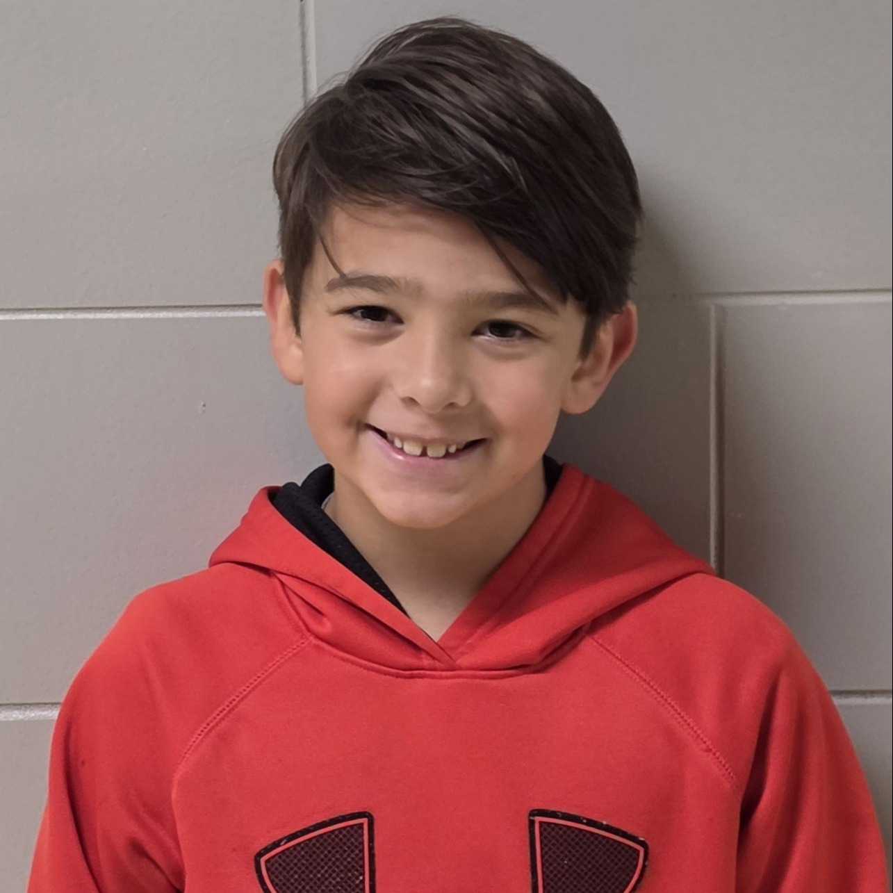 smiling boy with brown hair wearing a red hooded sweatshirt