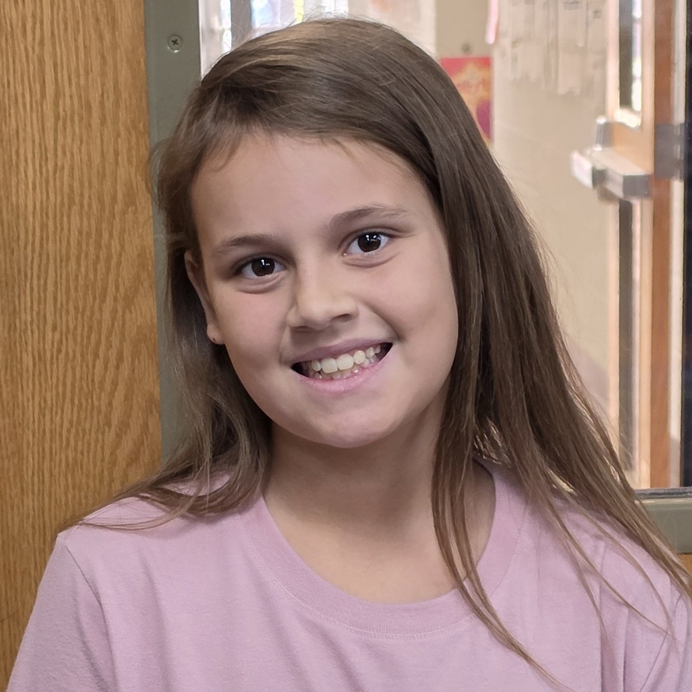 smiling girl with brown hair wearing a light purple t-shirt