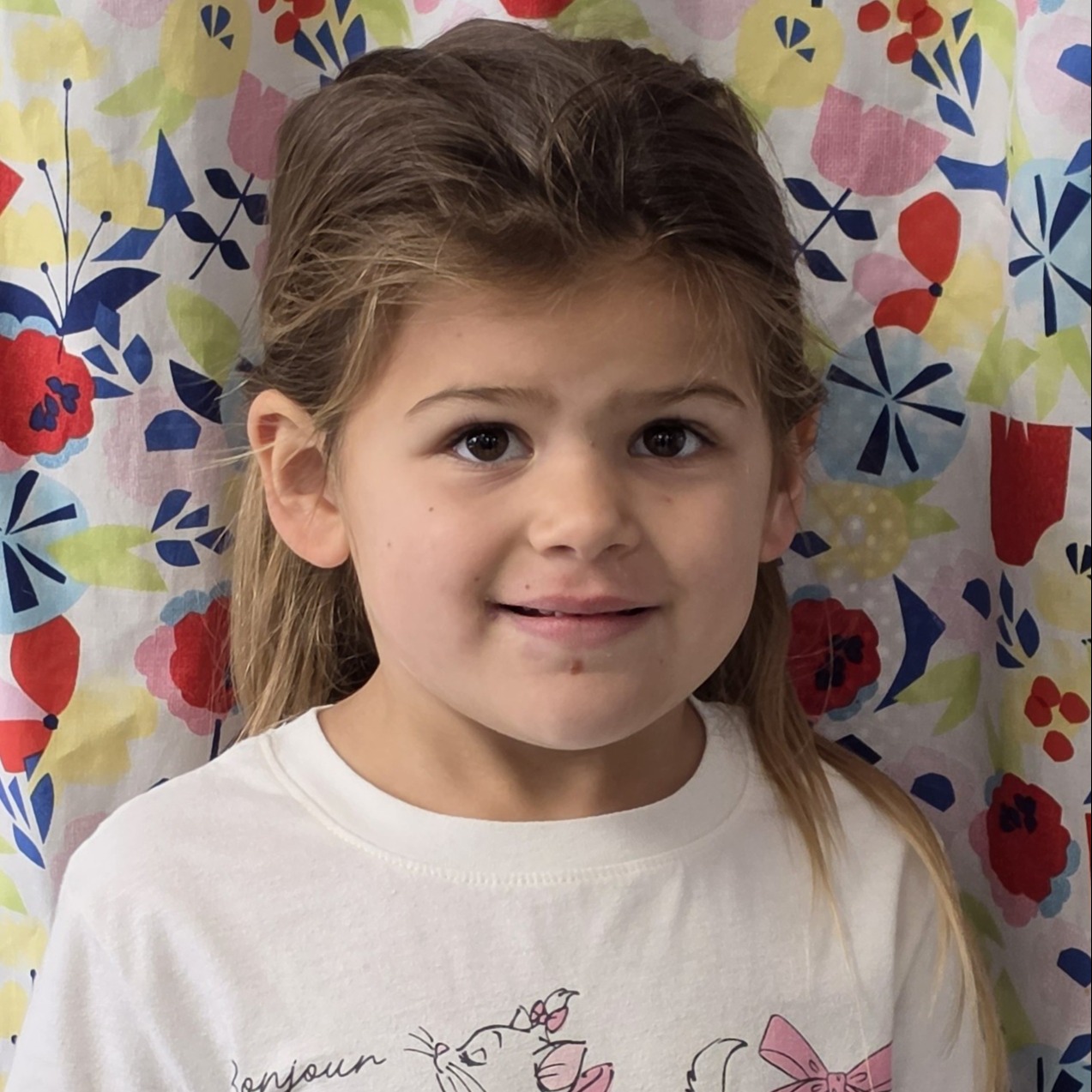 young girl with brown hair pulled back wearing a pink t-shirt