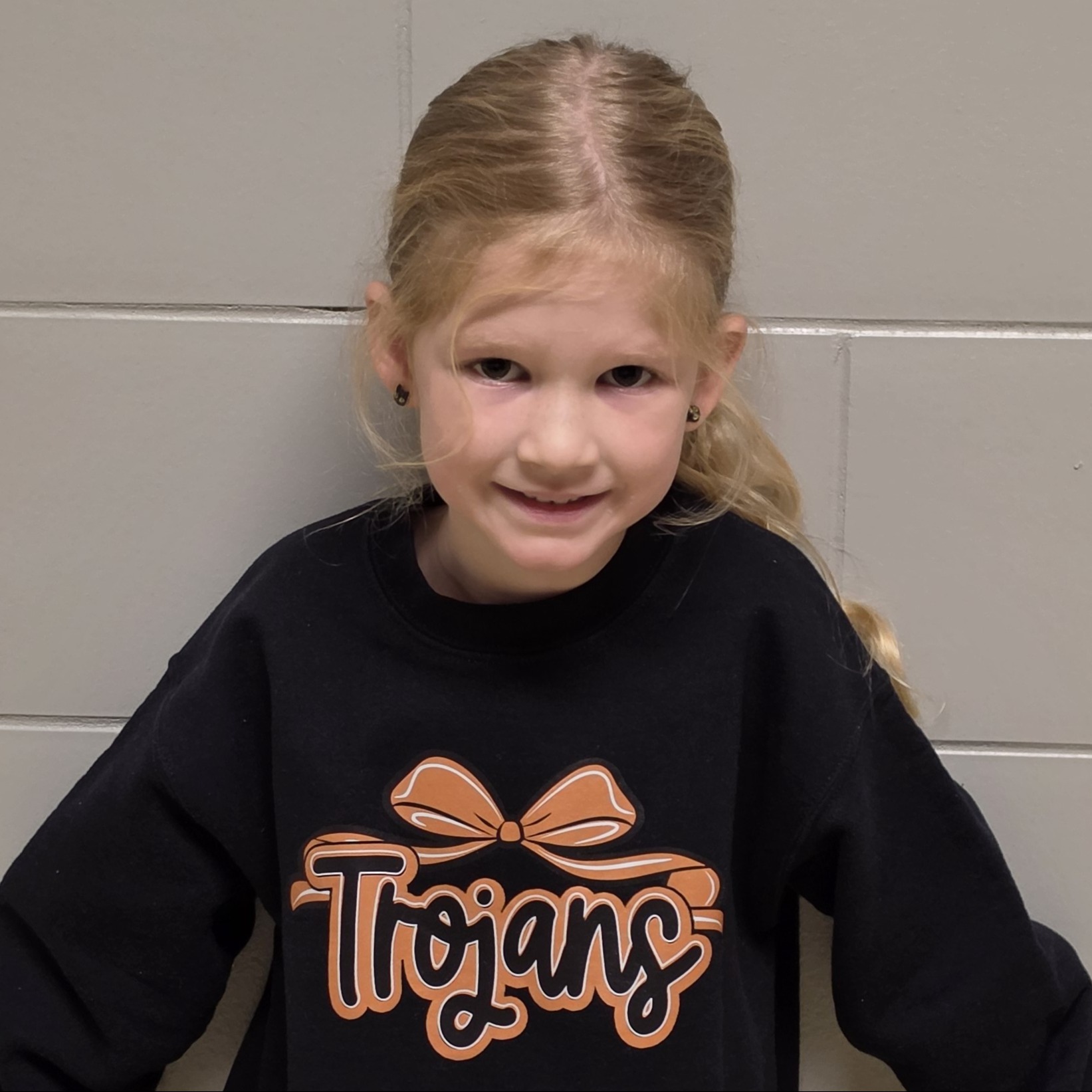 smiling girl with blonde hair pulled back wearing a black Trojans sweatshirt