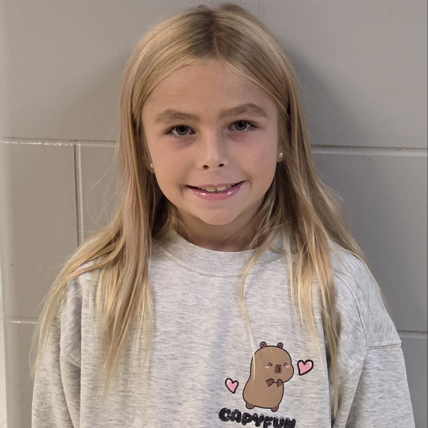 smiling girl with blonde hair wearing a gray sweatshirt