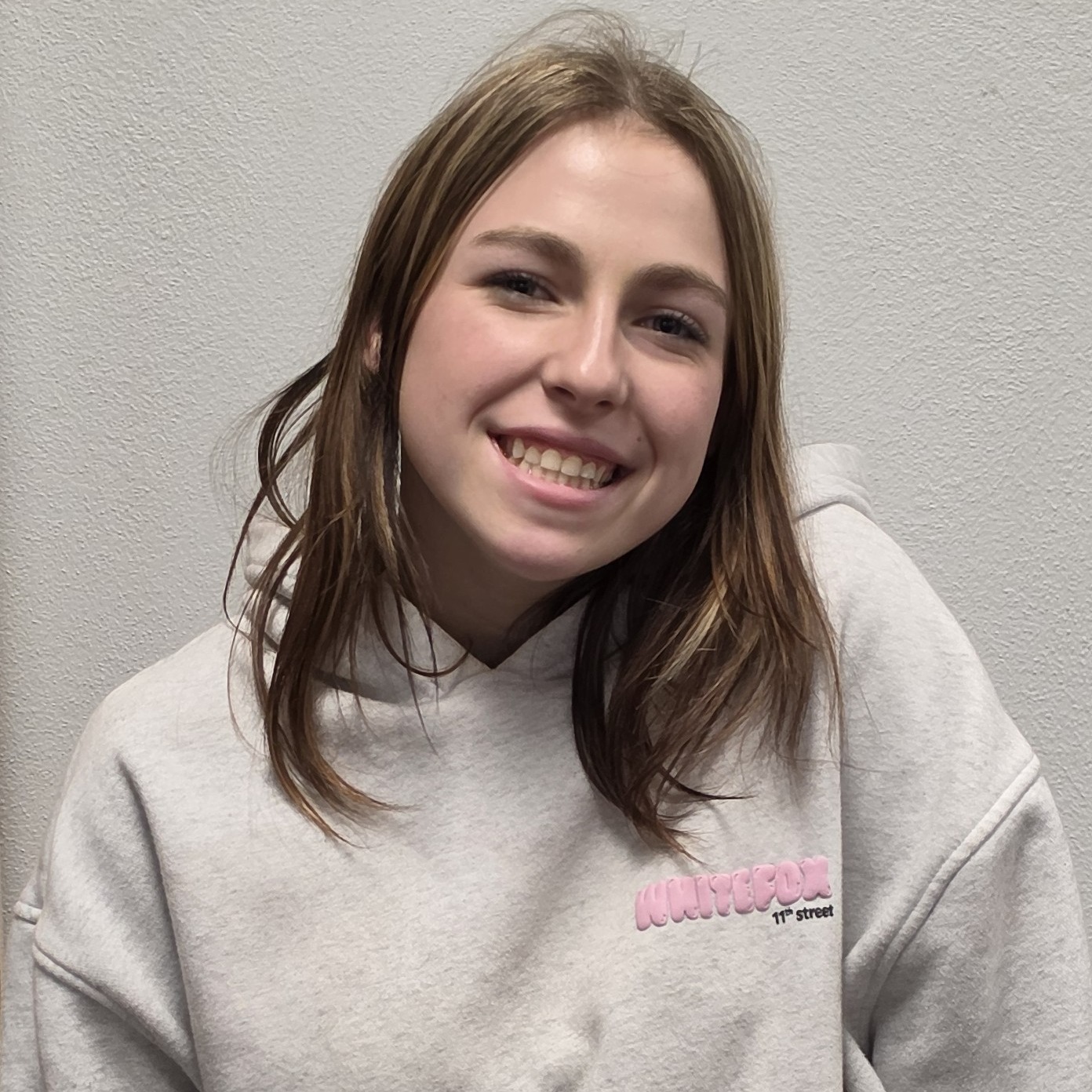 smiling young lady with  dark blonde hair wearing a gray hoodie